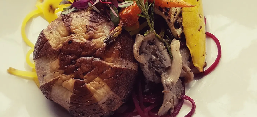 Close-up of cooked meat with herbs and vegetables.