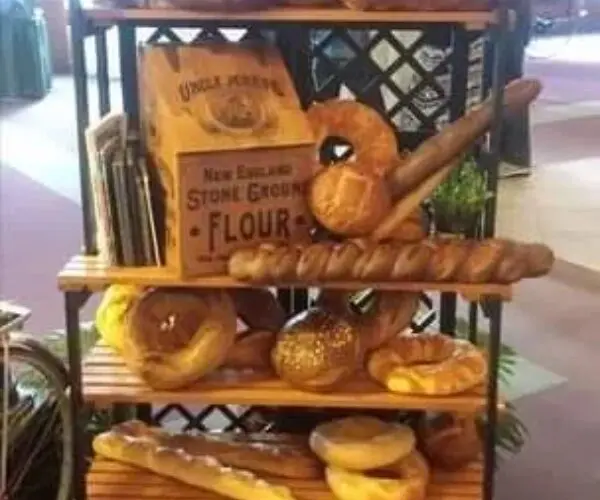 A bakery display with various artisanal breads and a rustic sign.