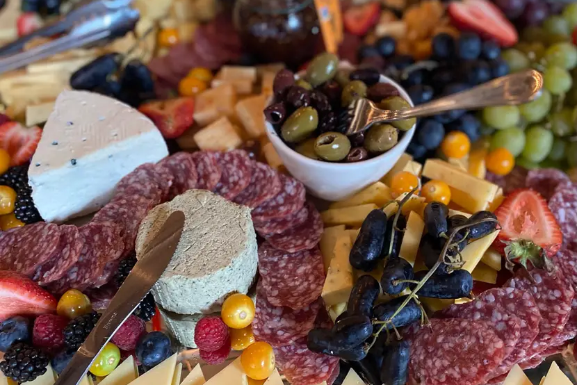 A platter featuring salami, cheese, olives, and nuts.